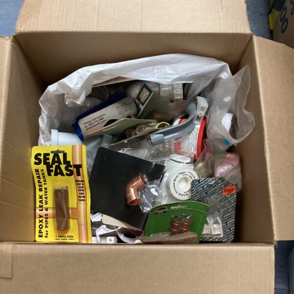 Assorted plumbing parts and fittings in a cardboard box.