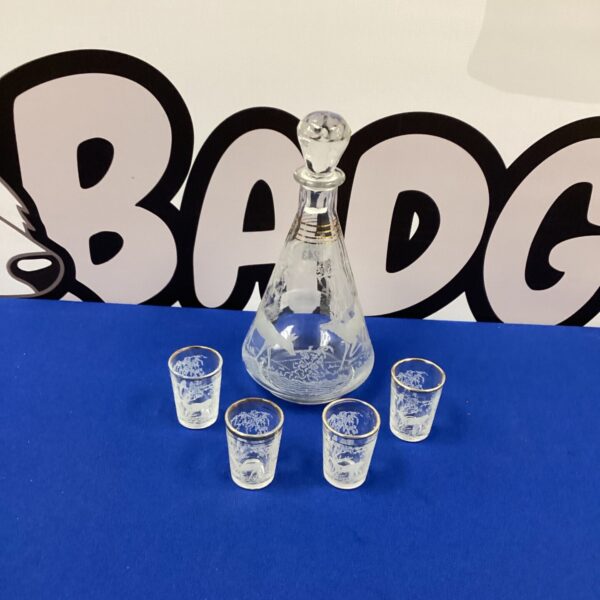 Vintage cut glass decanter set with four glasses on a dark surface.