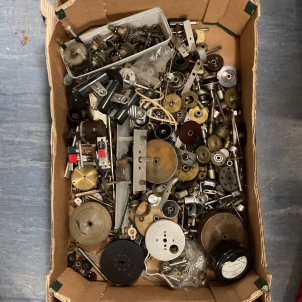 A box filled with a variety of vintage gears, cogs, and gauges.