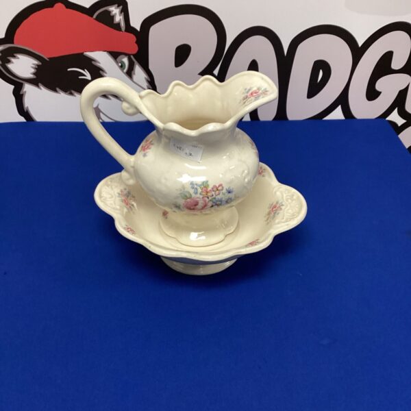 Vintage floral ironstone jug and stand on a white surface.