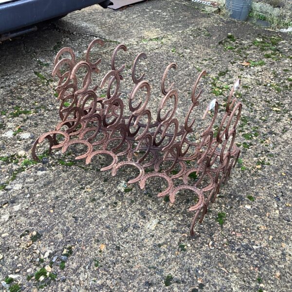 Rustic horse shoe boot rack displayed outdoors.