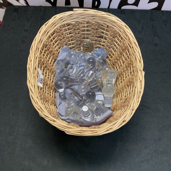 Wicker basket filled with assorted crystal decanter stoppers.
