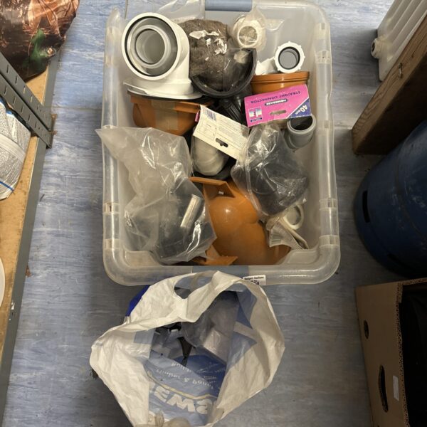 Assorted plastic drainage fittings in a box for plumbing projects.