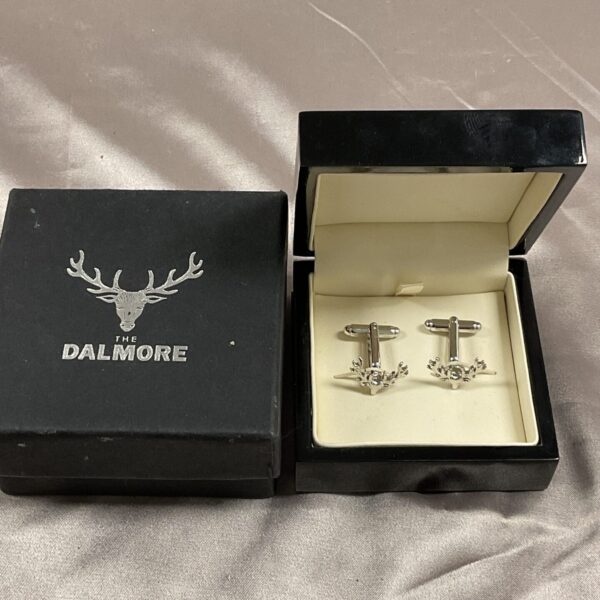 The Dalmore stag head cufflinks on a display card.