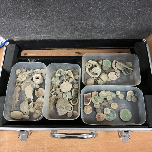 Aluminium case filled with a variety of corroded metal detector finds and coins.