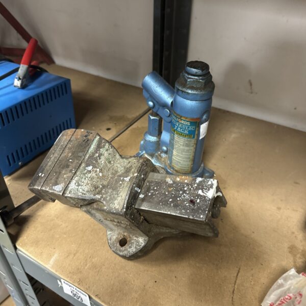 Vintage bench vice and blue bottle jack for workshop repairs.