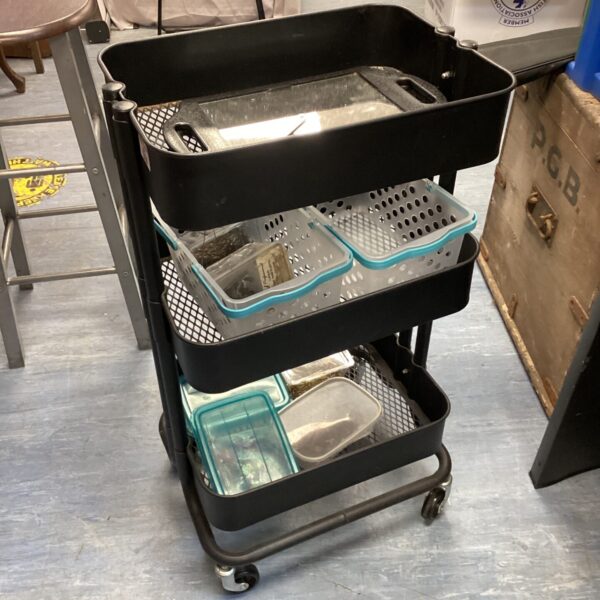 Metal tiered storage trolley with mesh trays for easy access.