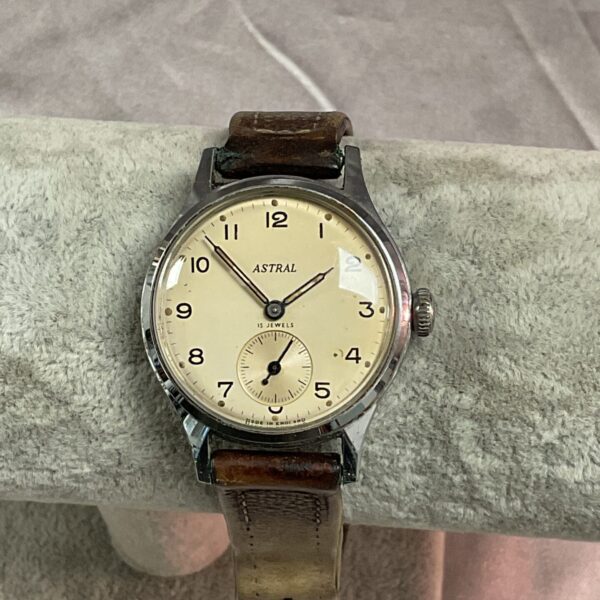 Vintage Astral wristwatch with cream dial and black numerals.