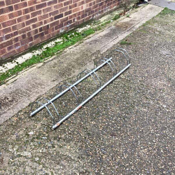 Stainless steel bike storage rack in a garden setting.