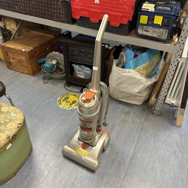 Vax Power 2 upright hoover in a cluttered room.