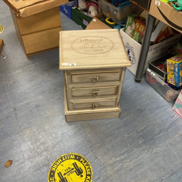 Shabby chic bedside cabinet with three drawers in a vintage bedroom setting.
