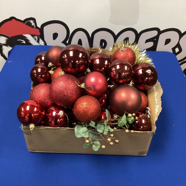 Red Christmas baubles and ornaments in a rustic wooden box.