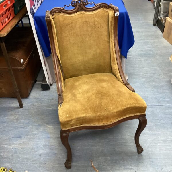 Yellow upholstered vintage nursing chair with carved wooden legs.