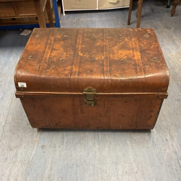 Front view of a vintage metal travel trunk with handles.
