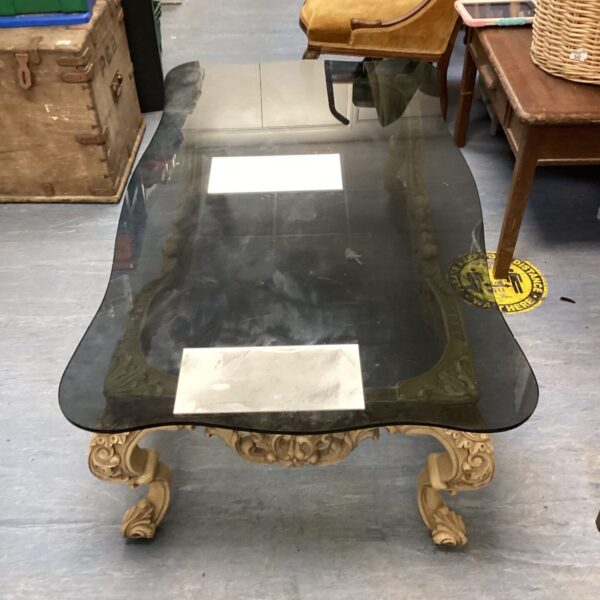 Ornate vintage glass top coffee table with carved legs.