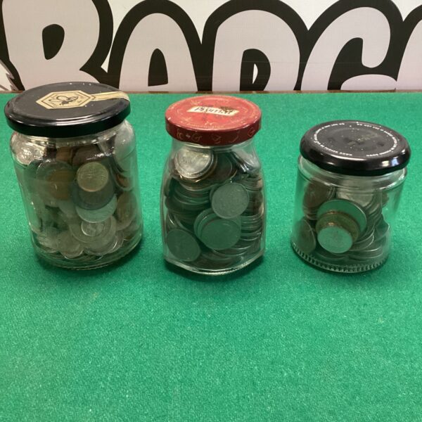 Three glass jars filled with mixed foreign coins for collectors.