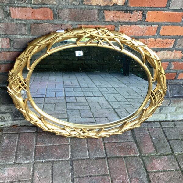 Vintage gilt framed oval mirror for wall decoration.