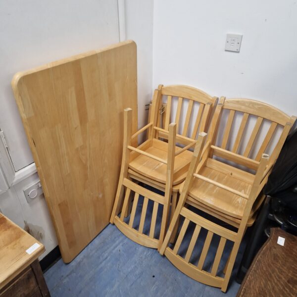 Wooden dining table and four chairs in farmhouse style.