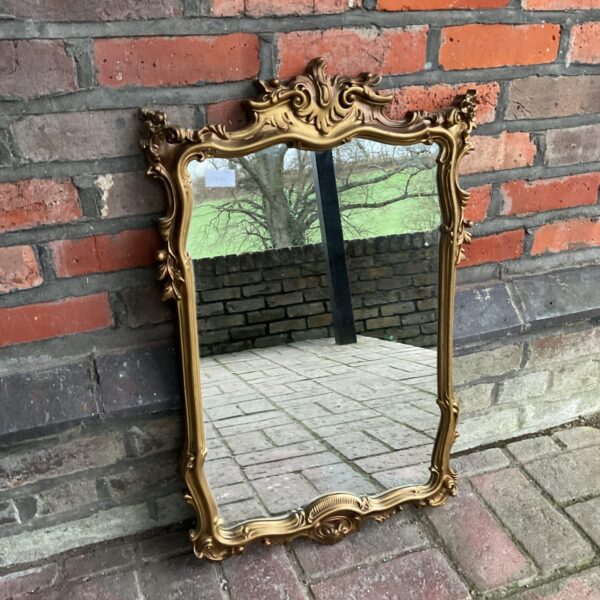 Ornate gilt framed French boudoir mirror for wall decoration.