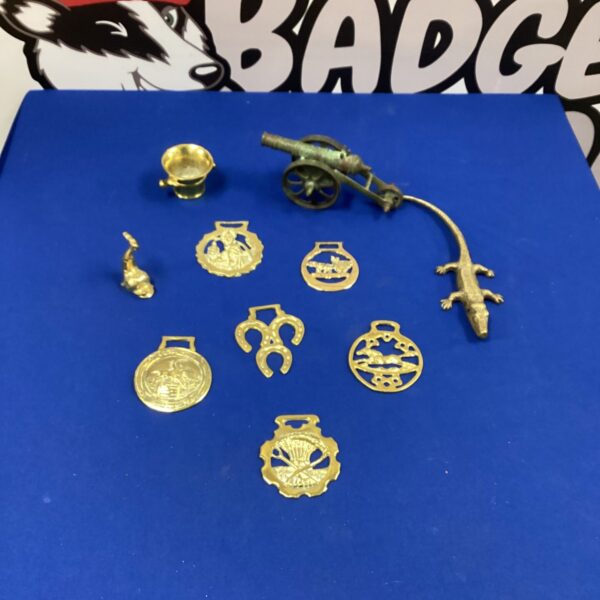 Vintage brass items including a dish, cannon, and decorative plaque.