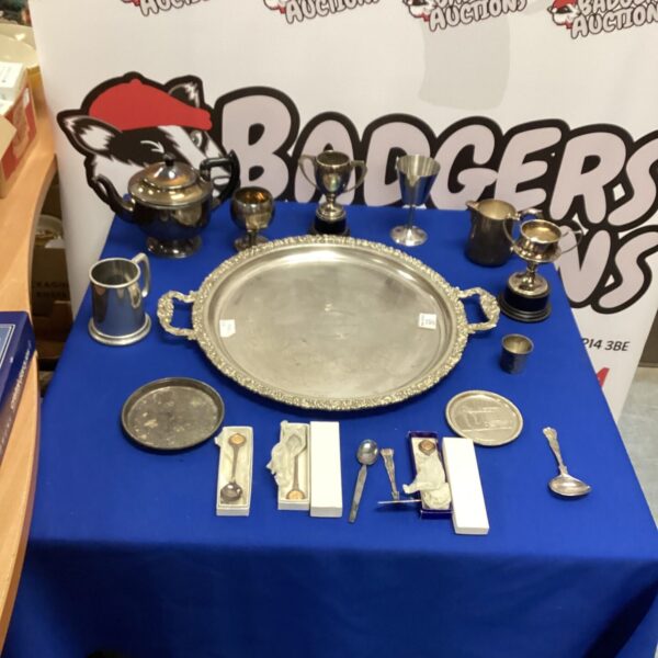 Vintage silverplated teapot and mixed silverware lot on display.