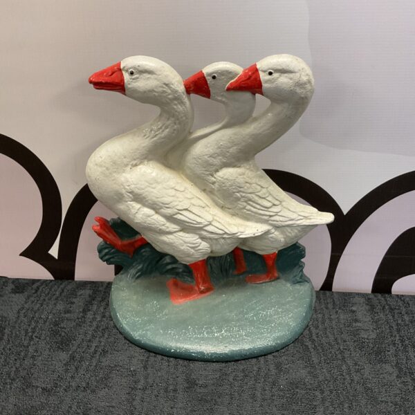 Vintage cast iron goose doorstop with three geese.