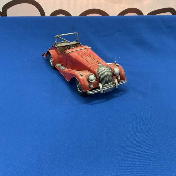 Vintage red tinplate model Morgan sports car collectible.