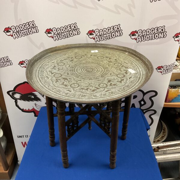 Intricate Indian brass charger table with folding wooden base.