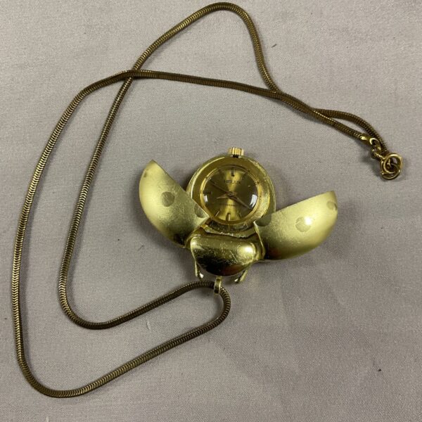 Close-up of vintage ladybird pendant necklace with watch.