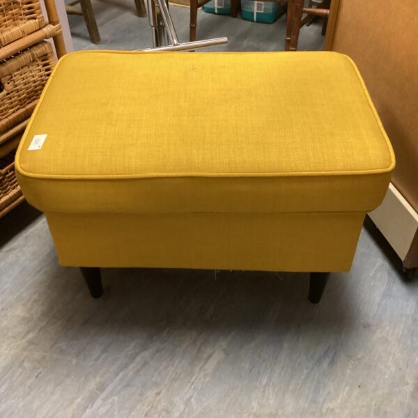 Bright yellow Ikea footstool with wooden legs.