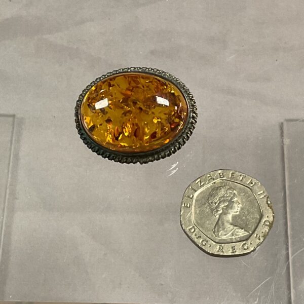 Vintage silver brooch with amber stone, close-up view.