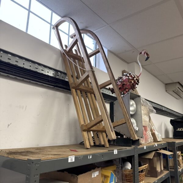 Vintage wooden sled with woven seat and curved runners.