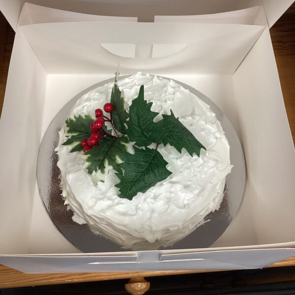 Festive Christmas cake decorated with holly, supporting dog rescue charity.