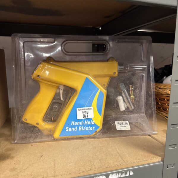 Close-up of a handheld sand blaster gun, showing its nozzle and trigger.