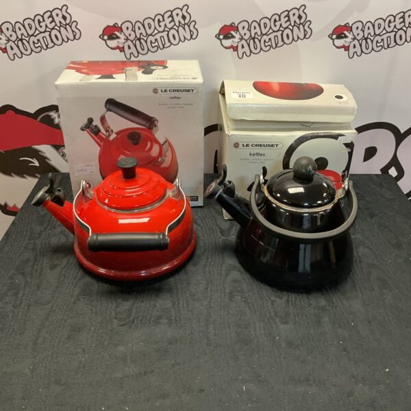 Red and black Le Creuset kettles on display.