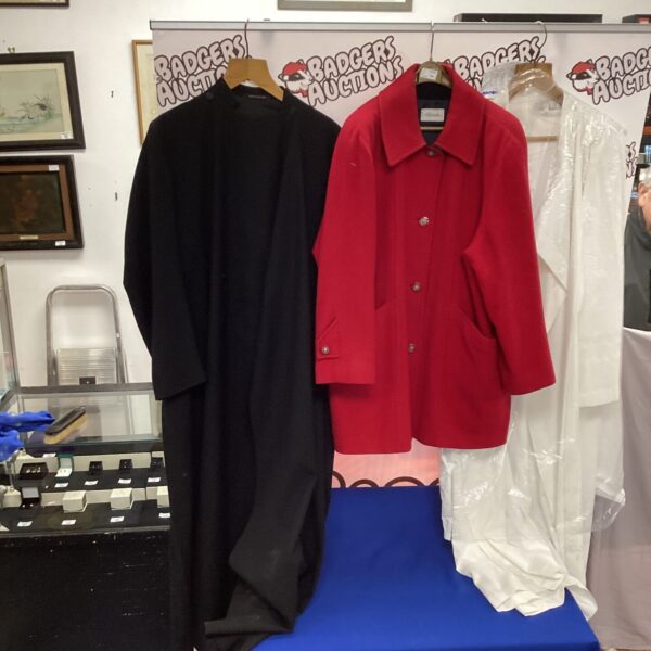 Black priest cassocks and a red coat displayed for auction.