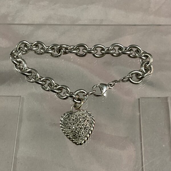 Close-up of a sterling silver heart bracelet with a detailed pendant.