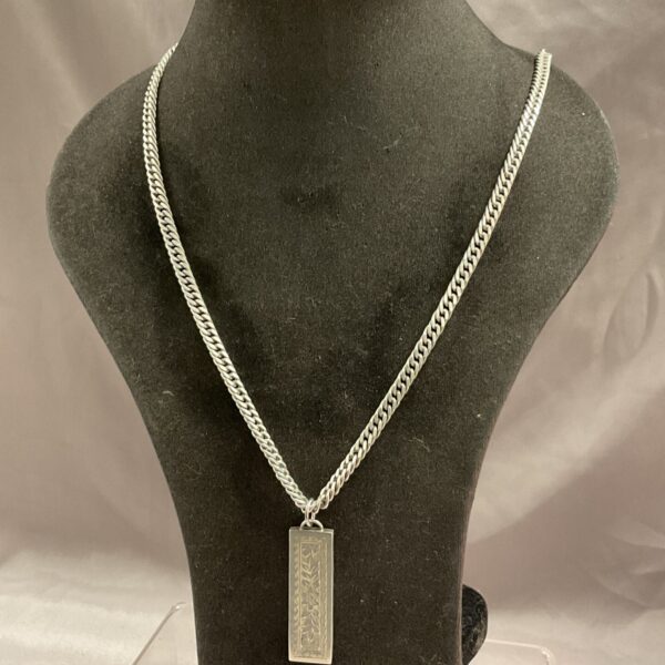 Silver ingot pendant necklace displayed on a mannequin.