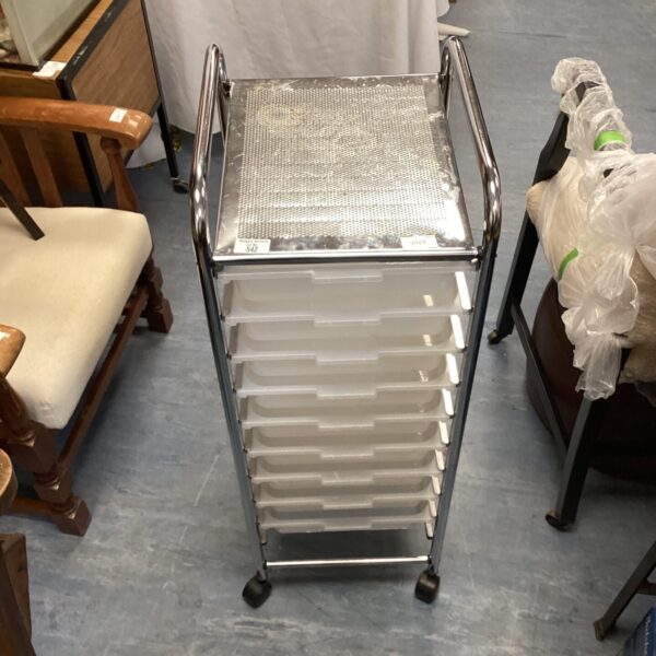 Chrome storage trolley with plastic drawers on wheels.