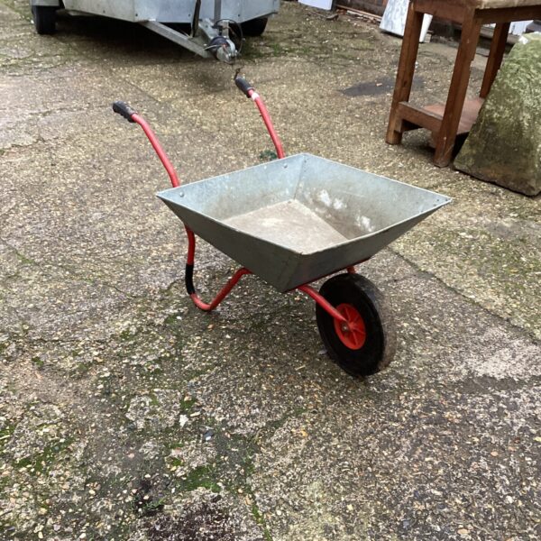 Galvanised steel wheelbarrow in a garden setting.