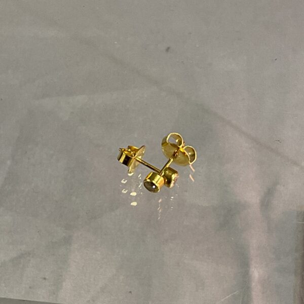 Close-up of 9ct gold stud earrings with secure butterfly fittings.