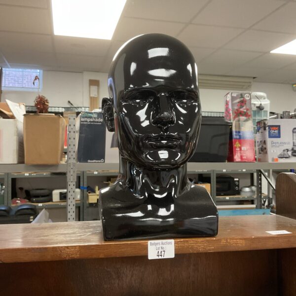 Dark plastic mannequin head for cosmetology practice.