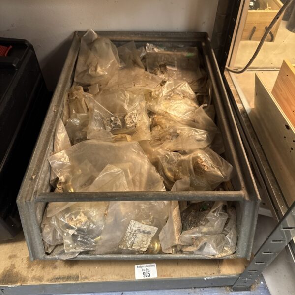 Assorted vintage brass drawer pulls and knobs in a metal tray.