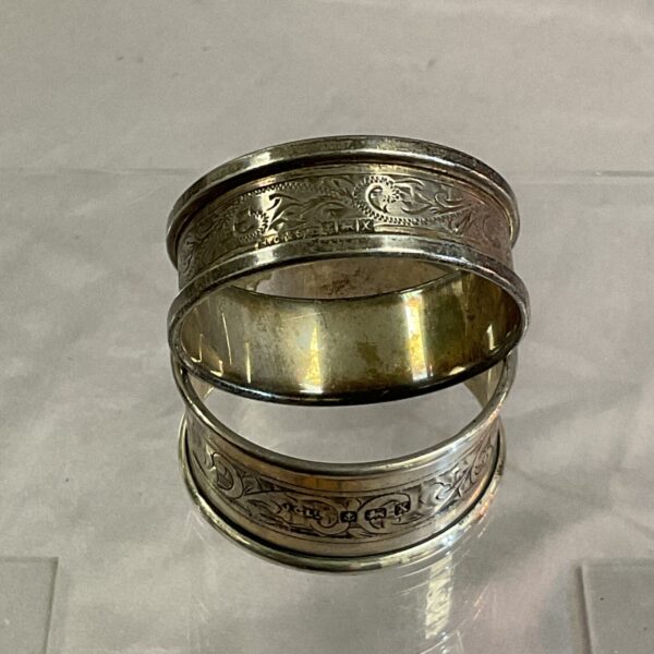 Stacked pair of antique silver napkin rings with floral design.