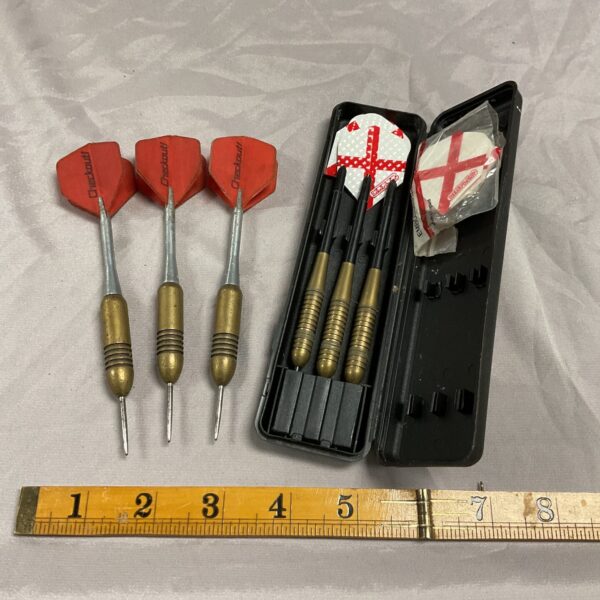 Vintage brass dart set with red flights in a black case.