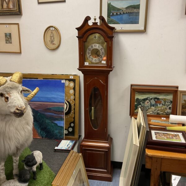 Antique grandmother clock with a wooden case and visible pendulum.