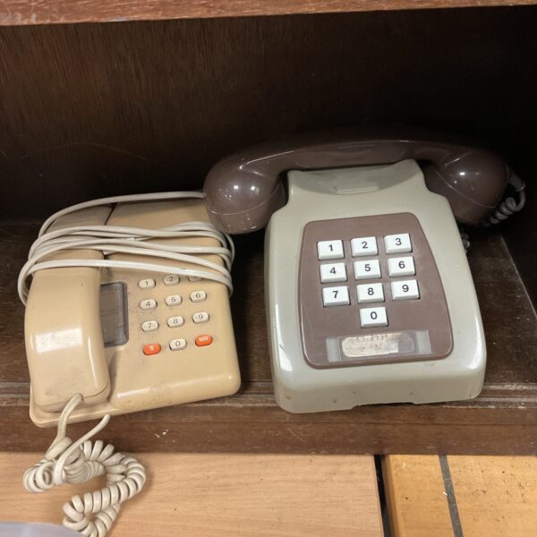 Vintage telephones lot, cream wall and desk models.