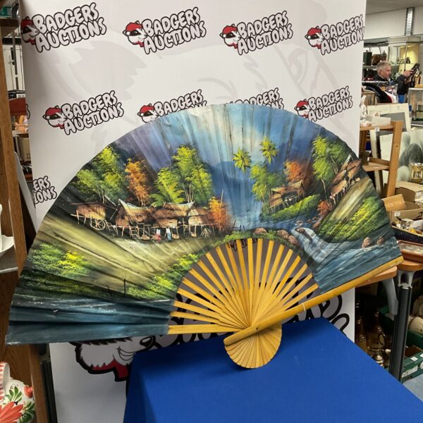 Large hand painted wall fan with detailed landscape scene.