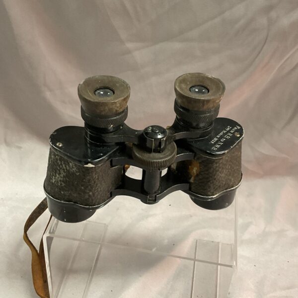 Front view of vintage WWI binoculars with leather strap.