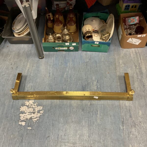 Antique brass fireplace fender with patina and wear.